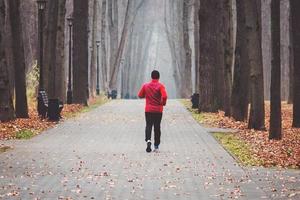 Coureur un matin terne dans un parc d'automne brumeux photo