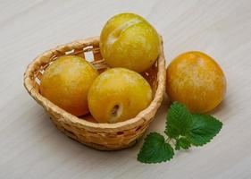 prunes jaunes dans un panier sur fond de bois photo