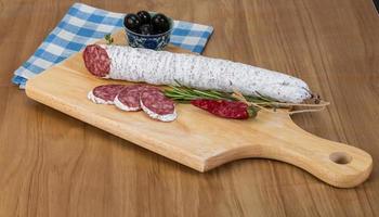 Saucisse fuet sur planche de bois et fond de bois photo