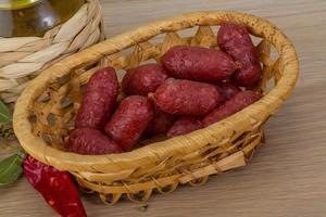 Mini salami dans un panier sur fond de bois photo