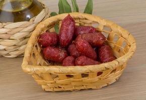 Mini salami dans un panier sur fond de bois photo