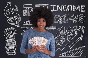 femme noire tenant de l'argent sur fond gris photo