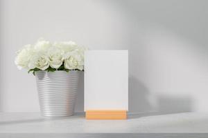 maquette de carte de voeux debout sur la table avec des roses blanches