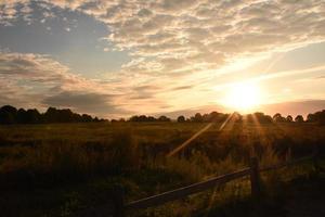 soleil levant sur un champ par temps nuageux photo