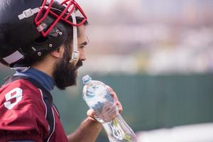 joueur de football américain buvant de l'eau après un entraînement intensif photo