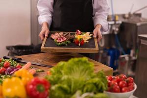 femme chef tenant une assiette de steak de boeuf photo