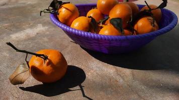 mandarines agrumes dans un panier violet sur fond de ciment exposé 03 photo