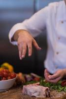 chef mettant du sel sur une tranche juteuse de steak cru photo