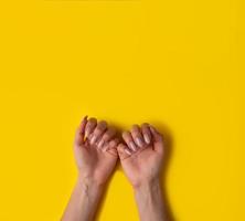 mains féminines avec une belle manucure sur fond jaune, vue de dessus photo
