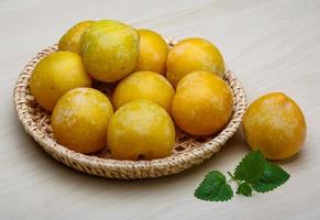 prunes jaunes dans un panier sur fond de bois photo