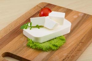 Fromage feta sur planche de bois et fond de bois photo