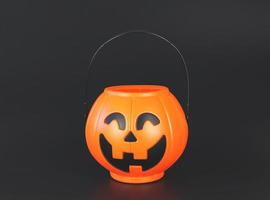 seau de citrouille d'halloween en plastique isolé sur fond noir avec espace de copie. concept de vacances d'halloween. photo