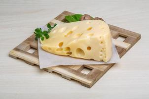 Fromage jaune sur planche de bois et fond de bois photo