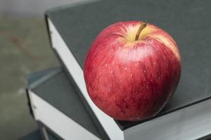 pomme sur la pile de livre sur l'étude de table en bois vert. photo