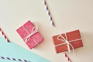 deux coffrets cadeaux emballés dans du papier à pois violet et rouge sur fond rose. photo