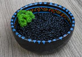 caviar noir dans un bol sur fond de bois photo