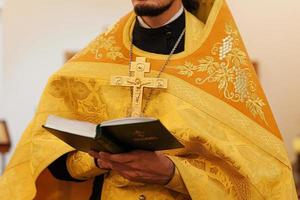 église orthodoxe. christianisme. mains de prêtre tenant le livre de la sainte bible dans le contexte traditionnel de l'église orthodoxe le jour du mariage, la veille de pâques ou la célébration de noël. religion foi prier symbole photo