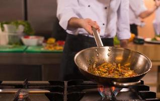 chef retournant les légumes au wok photo