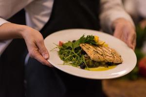 mains de chef tenant un plat de filet de poisson saumon frit photo