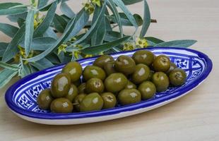 olives vertes dans un bol sur fond de bois photo