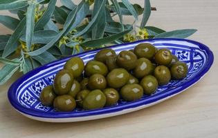 olives vertes dans un bol sur fond de bois photo