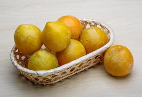 prunes jaunes dans un panier sur fond de bois photo