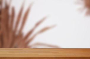 table en bois vide avec des feuilles floues sur fond blanc adaptée à la maquette d'affichage du produit photo