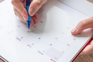 main de femme avec un stylo écrit sur la date du calendrier concept de réunion de rendez-vous de planification d'entreprise photo