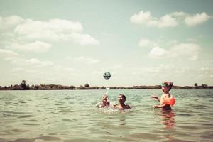 garçons heureux jouant avec le ballon dans l'eau pendant la journée d'été. photo