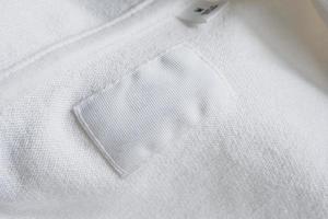 Étiquette de vêtements blancs vierges sur fond de chemise en coton neuf photo