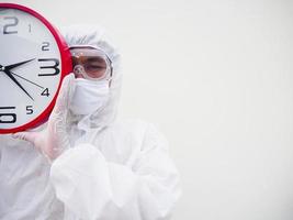 portrait d'un médecin ou d'un scientifique en uniforme de suite epi tenant un réveil rouge et regardant la caméra dans divers gestes. concept covid-19 isolé fond blanc photo