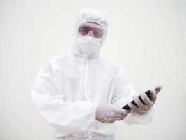 jeune médecin ou scientifique en uniforme de suite ppe tout en jouant de son téléphone pour discuter avec sa famille ou son ami et en regardant la caméra. coronavirus ou covid-19 concept isolé fond blanc photo