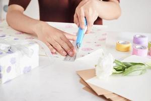 détail des mains de femme emballant des cadeaux avec du papier cadeau photo