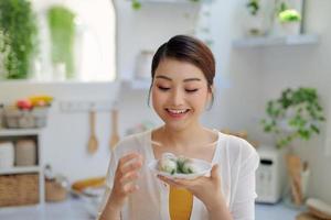 Femme asiatique mangeant des rouleaux de printemps sur fond de cuisine photo