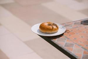 petit déjeuner matin ensoleillé temps chaud avec beignet sur plaque blanche sur fond de table. bonne humeur vue horizontale photo