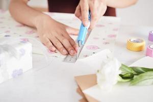 détail des mains de femme emballant des cadeaux avec du papier cadeau photo