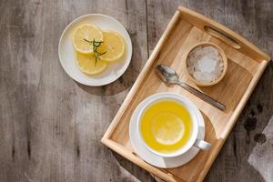 tasse de thé au gingembre au citron. tasse de thé au gingembre au citron. tasse en verre de thé chaud vert sur table en bois. tranches de citrons sur une planche à découper photo