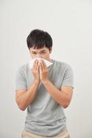 l'homme est malade et éternue avec un fond blanc, asiatique photo