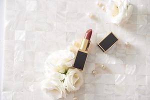 rouge à lèvres avec de belles fleurs sur fond blanc photo