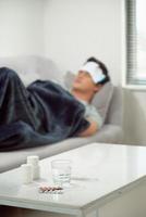 homme gaspillé malade allongé dans un canapé souffrant du virus de la grippe froide et hivernale ayant des comprimés de médecine dans le concept de soins de santé regardant la température sur le thermomètre photo