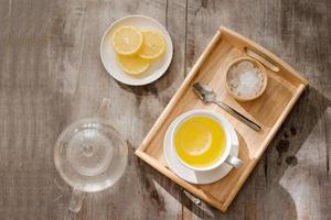 tasse de thé au gingembre au citron. tasse de thé au gingembre au citron. tasse en verre de thé chaud vert sur table en bois. tranches de citrons sur une planche à découper photo