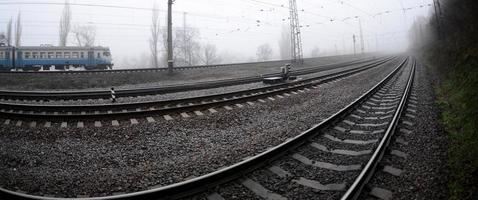 le train de banlieue ukrainien se précipite le long de la voie ferrée par un matin brumeux. photo fisheye avec distorsion accrue