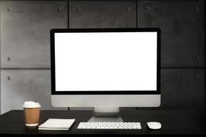 vue rapprochée de l'ordinateur à écran blanc, des fournitures de bureau et de la décoration sur un bureau blanc avec un arrière-plan flou de la salle de bureau moderne photo