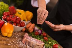 chef mettant du sel sur une tranche juteuse de steak cru photo