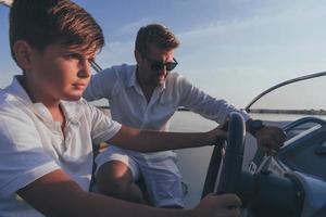 père et fils profitent de leurs vacances ensemble tout en conduisant un bateau de luxe en mer. mise au point sélective photo