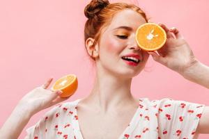 belle fille en haut blanc avec imprimé cerise posant avec des oranges sur fond isolé