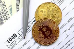 le stylo, les bitcoins et les billets d'un dollar se trouvent sur le formulaire fiscal 1040 déclaration de revenus des particuliers américains. le temps de payer les impôts photo