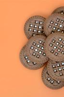 image détaillée de biscuits sandwich ronds brun foncé fourrés à la noix de coco sur une surface orange. image de fond d'un gros plan de plusieurs friandises pour le thé photo