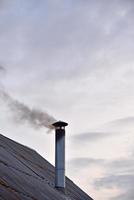 la cheminée en fer fumante d'une vieille maison le soir. photo