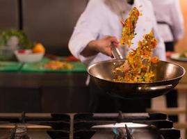 chef retournant les légumes au wok photo